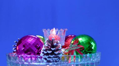 Cam bir zemin üzerinde mavi bir zemin, yanan bir mum etrafında Noel süslemeleri