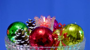 Cam bir zemin üzerinde mavi bir zemin, yanan bir mum etrafında Noel süslemeleri