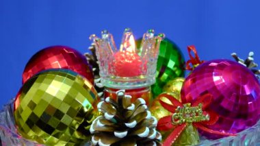 Cam bir zemin üzerinde mavi bir zemin, yanan bir mum etrafında Noel süslemeleri