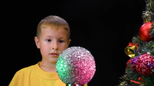 Malý Chlapec Zkoumá Točící Stříbrný Míček Zdobeného Vánočního Stromečku — Stock video
