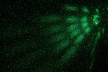 Light green rays of light on a dark green finely grained background