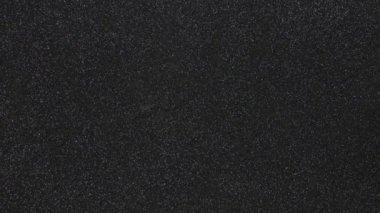 Monotonous black background in fine grain in motion from bottom to top