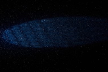 On a black background, a fine-grained background, a colored corrugated cloud of light