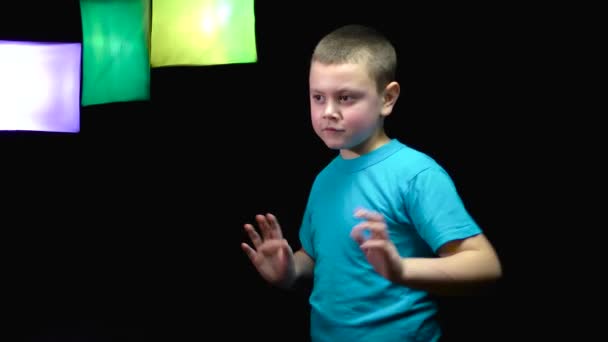 一个有着变色聚光灯的黑色背景的快乐男孩 — 图库视频影像
