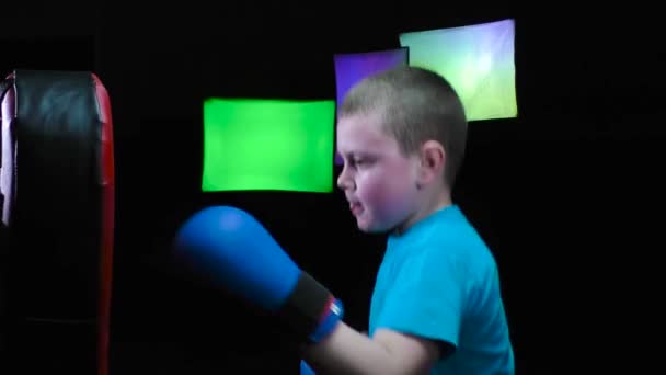 男孩运动员手上架着蓝色的套头毛衣 在黑色的背景上 用变色的聚光灯来训练冲刺动作 — 图库视频影像