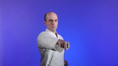 Mavi arka planda, yetişkin bir sporcu yumrukları yener