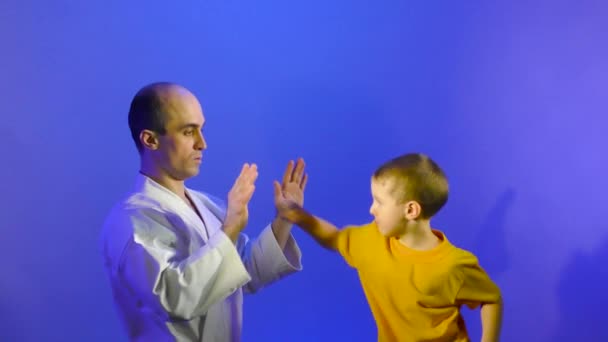在蓝色背景下 爸爸和儿子正在练习手部击球 — 图库视频影像