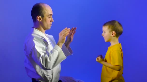 Een Blauwe Achtergrond Trainen Vader Zoon Handslagen Handpalmen — Stockvideo