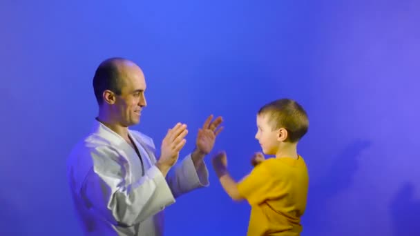在蓝色背景下 爸爸和儿子正在练习手部击球 — 图库视频影像