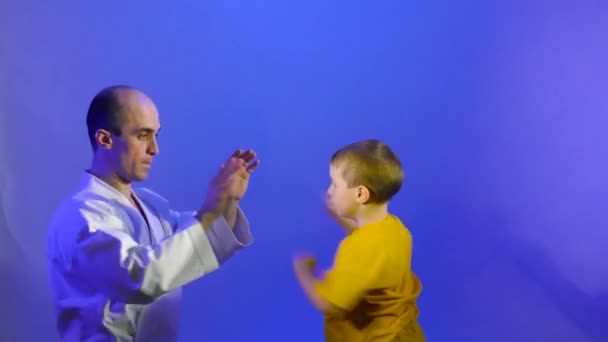 在蓝色的背景下 一个小男孩用手掌打一拳 — 图库视频影像