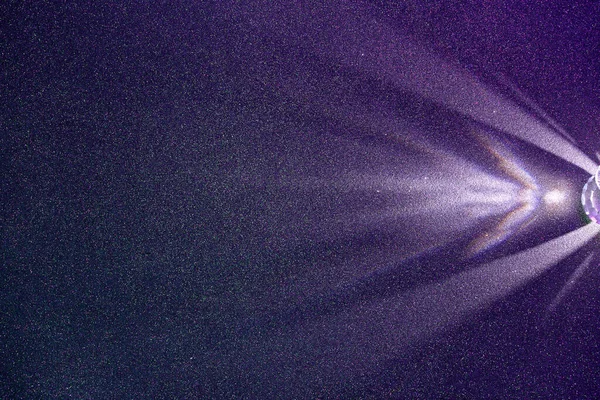 暗紫色の構造の微粒な背景では 光の薄紫散乱ビーム — ストック写真