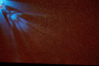 Koyu kırmızı bir arkaplanda açık mavi ışık demetleri