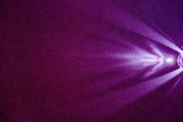 在黑暗的淡紫色结构细粒度背景上 一束浅紫色的散射光 — 图库照片