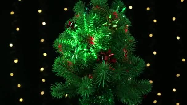 光の空飛ぶアニメーションで緑色の装飾されたクリスマスツリーは 点滅するライトで黒い背景に回転します — ストック動画