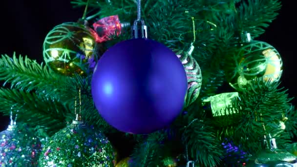 青いクリスマスボールは ボールで装飾されたクリスマスツリーの枝やガーランドの背景に対して回転します — ストック動画