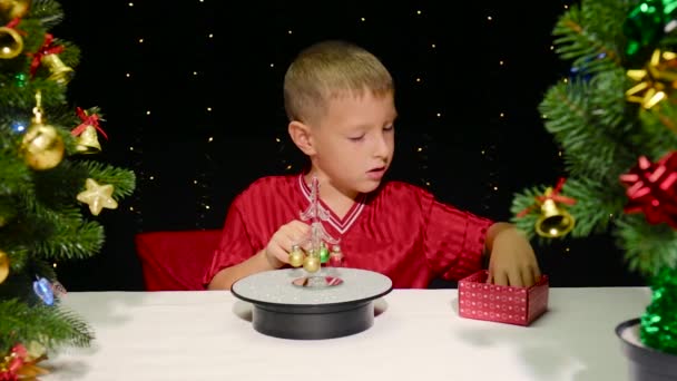 Umgeben Von Großen Weihnachtsbäumen Schmückt Ein Kleiner Junge Einen Kleinen — Stockvideo