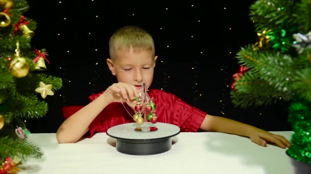 Umgeben Von Großen Weihnachtsbäumen Schmückt Ein Junge Einen Kleinen Weihnachtsbaum — Stockvideo