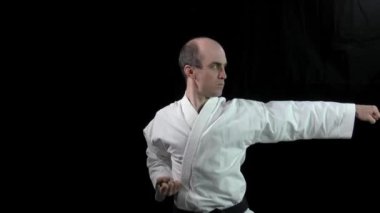 Siyah arka planda, yetişkin bir atlet resmi karate egzersizleri yapar.