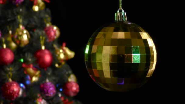 Μαύρο Φόντο Μια Κίτρινη Χριστουγεννιάτικη Μπάλα Περιστρέφεται Κοντά Ένα Διακοσμημένο — Αρχείο Βίντεο