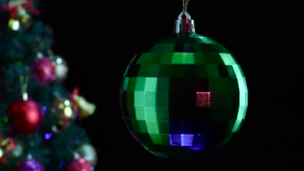 在黑色的背景上 一个绿色光滑的新年舞会在一棵装饰过的圣诞树旁旋转 — 图库视频影像