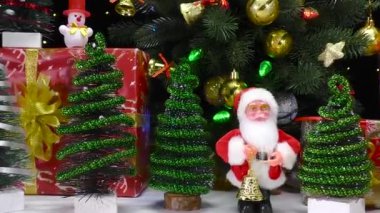 Noel Baba küçük köknar ağaçlarının yanında duruyor.