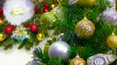Üzerinde yazı ve animasyon olan bir Noel çelengi önünde renkli topları olan bir Noel ağacının video kartpostalı.