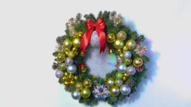 Beyaz arka planda büyük bir Noel çelengi. Toplar ve çanlarla süslenmiş.