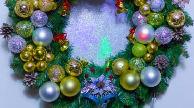 Açık mavi bir arka planda hareketli bir Noel çelengi renkli toplar ve çanlar ile süslenmiş büyük bir Noel çelengi