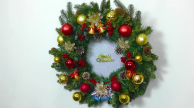 Noel, renkli toplar, çanlar ve ortasında bir yazıyla süslenmiş büyük bir Noel çelengidir.