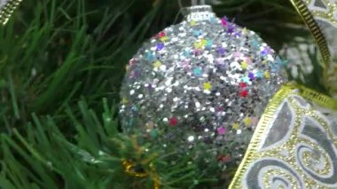 Yılbaşı topları ve Noel çanları olan bir Noel ağacının video kartpostalı. Üzerinde yazı olan bir Noel çelengi önünde dönüyor.