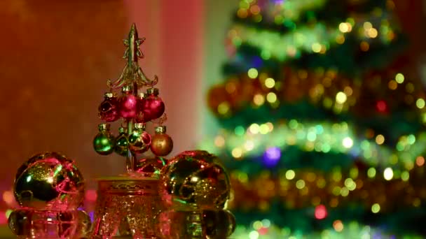在有圣诞树的半模糊的背景上 一棵装饰着小球的小圣诞树在黄色的球之间旋转 — 图库视频影像