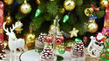 Bir Noel ağacı, büyük bir Noel ağacının yanında çam kozalaklarıyla çevrili bir tezgahta döner.