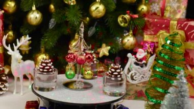 Küçük bir Noel ağacı, Noel özellikleri arasında çam kozalaklarıyla çevrili bir tezgahta döner.