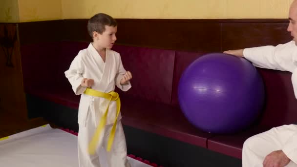 Chłopiec Wykonuje Okrągłe Kopnięcie Piłce Trzymanej Przez Trenera — Wideo stockowe