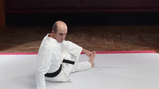 Athlete Black Belt Performs Back Stretch While Sitting Floor Stock Footage
