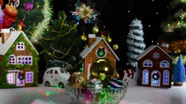 Dekorasyon evlerinin yakınında ve Noel Baba 'nın ortasında olduğu bir Noel çelengi. Farklı boyutlarda çok renkli Noel topları dönüyor.