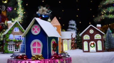 Mavi bir Noel ağacı olan küçük mavi bir ev Noel evlerinin arka planında dönüyor.