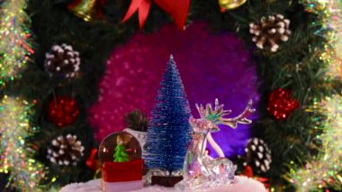 Noel Baba 'nın kızakla çevirdiği küçük bir Noel ağacı, bir geyik ve bir kızakla bir cam top, bir Noel çelenginin arka planında dönüyor.