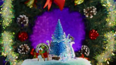 Noel ağacı Noel Baba 'nın kızağında, bir geyik ve bir kızakla süslü bir Noel çelenginin arka planında döner.