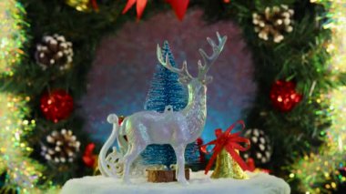 Noel geyiği çanı ağacı ve Noel Baba bir Noel çelengiyle kızakta dönüyorlar.