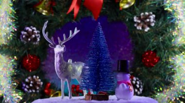 Noel geyiği kardan adam ve köknar ağacı gelişmekte olan bir çelengin arka planında dönerler