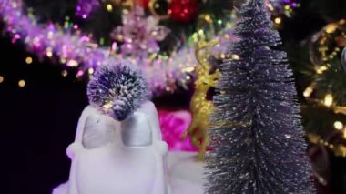 Bir Noel ağacı makinesinin yakın çekimi ve köknar ağaçlarının yanında dönen bir geyik ve bir Noel çelengi.