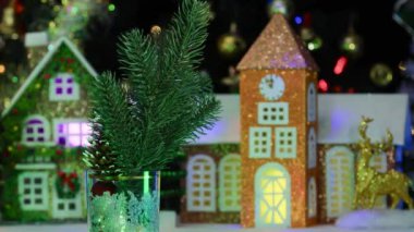 Noel 'de çam kozalağı küçük toplar ve Noel ağacı dalları dekore edilmiş evlerin arka planında dönüyor