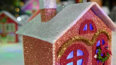 Noel hareketli, küçük, temiz, pencerelerinde renk değiştiren bir ev büyük bir Noel kasabasının arka planında dönüyor.