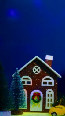 Uçan animasyonlarla dolu koyu mavi bir arka planda, renkli evleri ve renkli arabaları olan alışılmadık bir Noel kasabası.