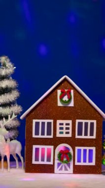 Uçan animasyonlarla dolu koyu mavi bir arka planda, Noel çelenkleri ve farklı Noel ağaçlarıyla süslenmiş evleri olan alışılmadık bir Noel kasabası.