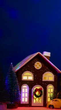 Uçan animasyonlarla dolu koyu mavi bir arka planda, dekore edilmiş çok renkli Noel ağaçları ve çok renkli arabaları olan alışılmadık bir Noel kasabası.