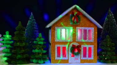 Noel çelengi ve renkli Noel ağaçları arasında uçan animasyonla süslenmiş iki katlı bir Noel evi.