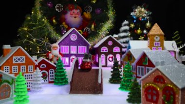 Noel hareket halindeyken Noel çelenkleriyle süslenmiş renkli Noel ağaçları ve evlerle dolu sihirli bir Noel kasabası