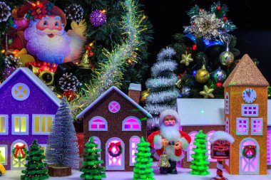 Evlerin camlarında mavi ve sarı ışıklar, Noel Baba ve Noel ağaçlarının farklı boyutlarda olduğu bir Noel kasabası.